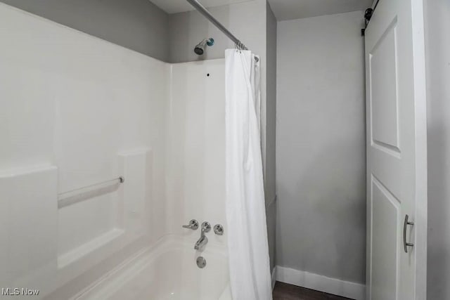 bathroom featuring shower / bathtub combination with curtain and baseboards