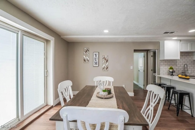dining space with baseboards, light wood-style floors, and a textured ceiling