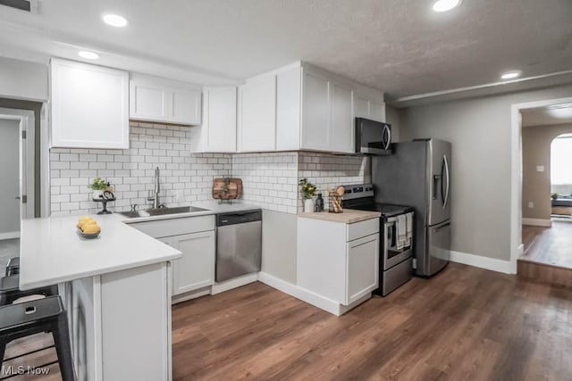 kitchen with stainless steel appliances, a peninsula, light countertops, and a sink
