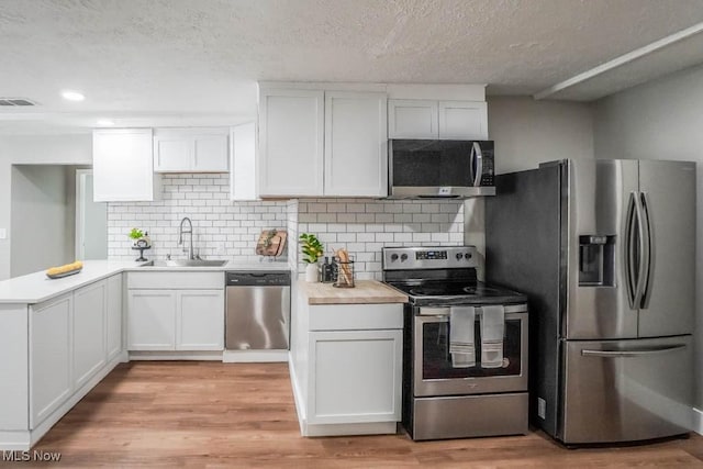 kitchen with visible vents, white cabinets, a sink, light countertops, and appliances with stainless steel finishes