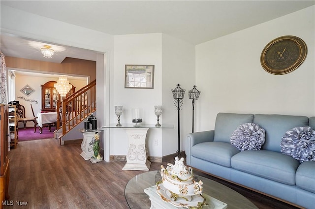 living room featuring dark wood-style flooring, baseboards, a notable chandelier, and stairs