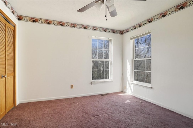 carpeted spare room featuring baseboards, a ceiling fan, and visible vents