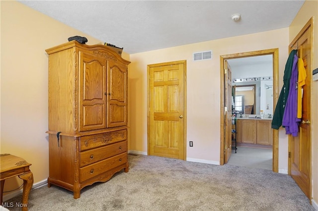 bedroom featuring light carpet, ensuite bathroom, baseboards, and visible vents