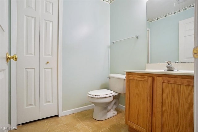 bathroom featuring a closet, vanity, tile patterned flooring, toilet, and baseboards