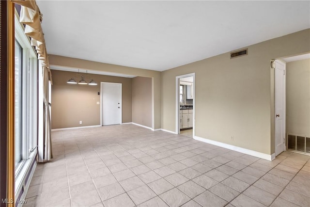 spare room featuring a baseboard radiator, visible vents, baseboards, and light tile patterned flooring