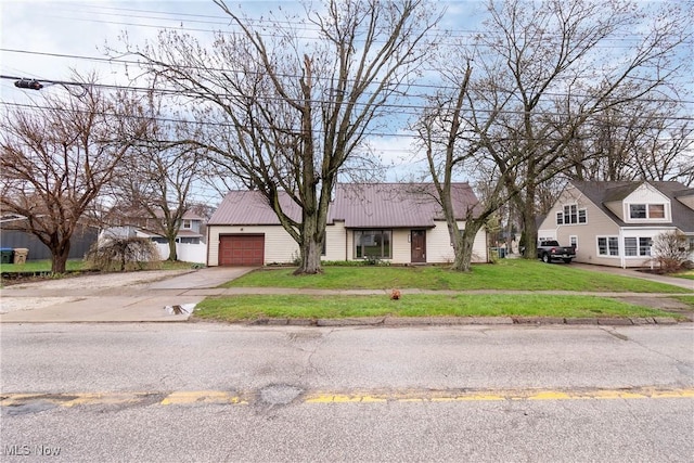 view of front of home featuring a front yard, metal roof, a garage, and driveway