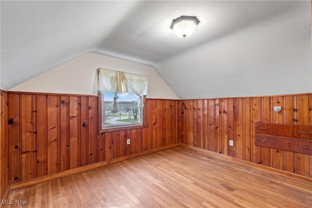 bonus room featuring wood finished floors, wooden walls, wainscoting, and vaulted ceiling