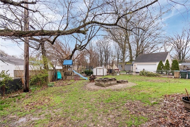 view of yard featuring a shed, a fenced backyard, an outdoor structure, a fire pit, and a playground