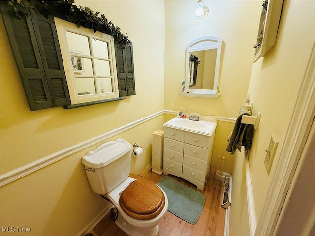 bathroom featuring wood finished floors, toilet, vanity, and baseboards