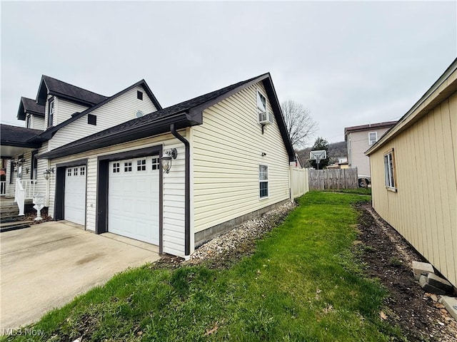 view of side of property with concrete driveway, a lawn, and fence