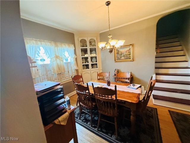 dining room featuring an inviting chandelier, stairway, light wood-style floors, and crown molding