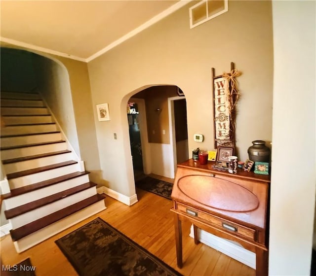 corridor with stairway, visible vents, baseboards, arched walkways, and wood finished floors