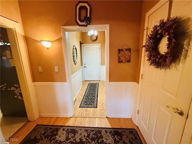 entryway with light wood-type flooring and a wainscoted wall