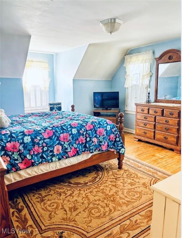 bedroom with wood finished floors and lofted ceiling