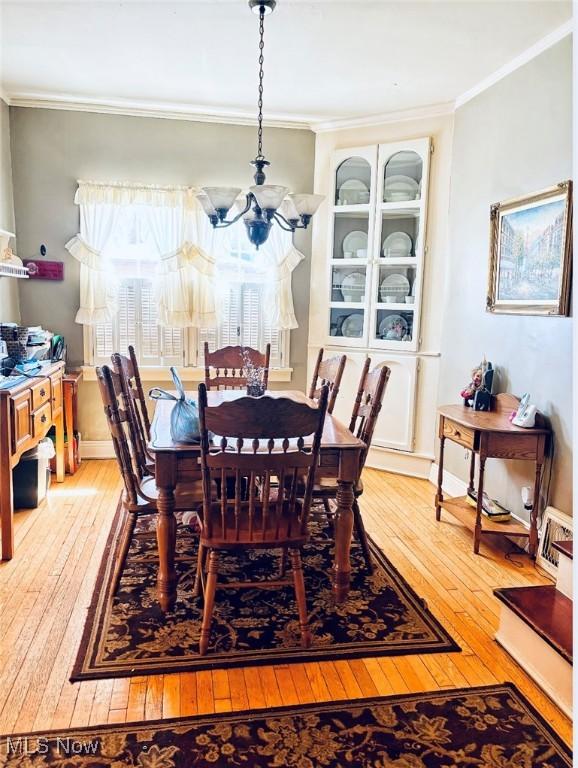 dining room with hardwood / wood-style floors, an inviting chandelier, and crown molding
