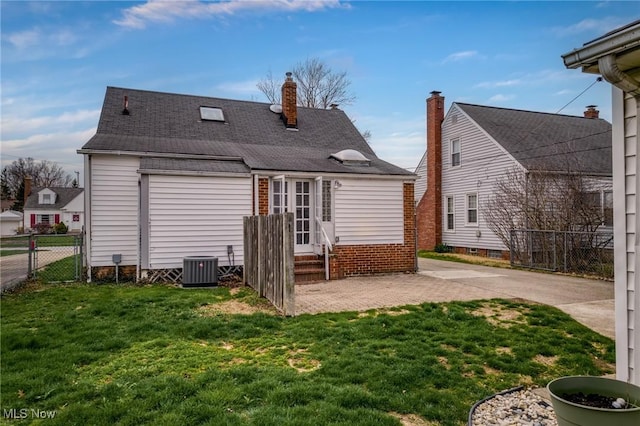 rear view of property with entry steps, central AC, fence, and a lawn