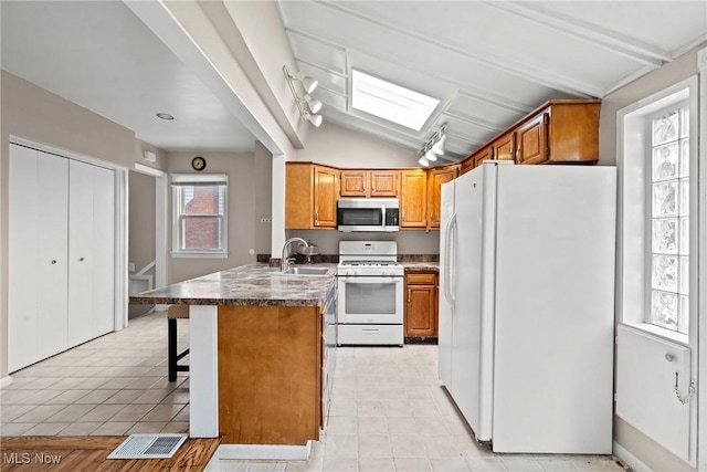 kitchen featuring white appliances, brown cabinetry, a peninsula, a sink, and lofted ceiling