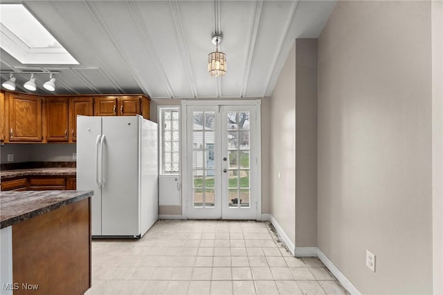 kitchen with light tile patterned floors, baseboards, dark countertops, freestanding refrigerator, and french doors