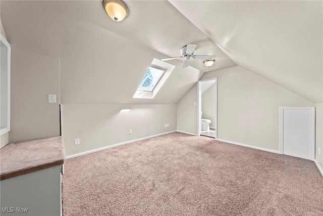 additional living space featuring carpet flooring, baseboards, and lofted ceiling with skylight