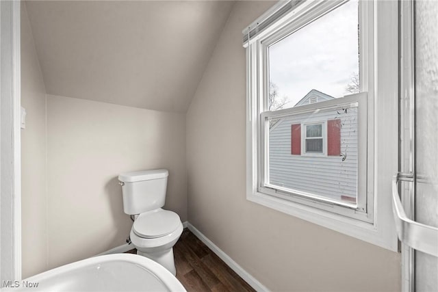 bathroom with toilet, vaulted ceiling, wood finished floors, and baseboards