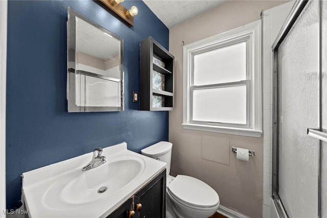 full bath featuring toilet, a shower with shower door, vanity, and a textured ceiling