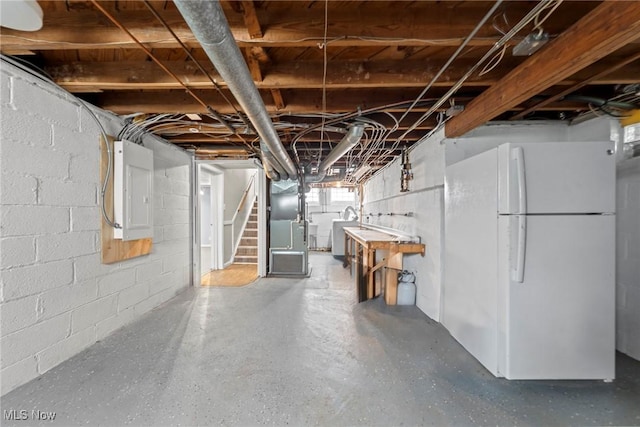 basement with electric panel, stairway, freestanding refrigerator, heating unit, and washer / dryer