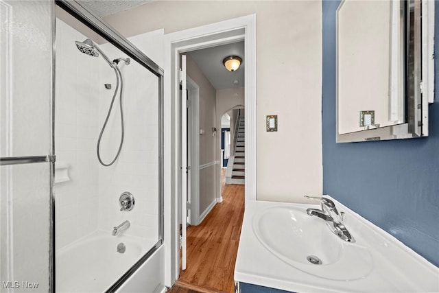 bathroom featuring a sink, wood finished floors, and shower / bath combination with glass door