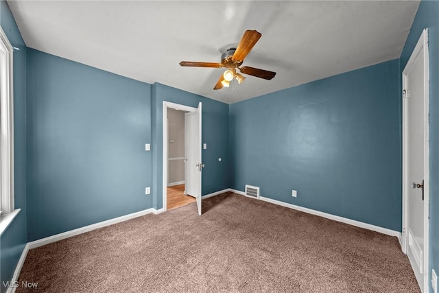 unfurnished bedroom with ceiling fan, visible vents, baseboards, and carpet