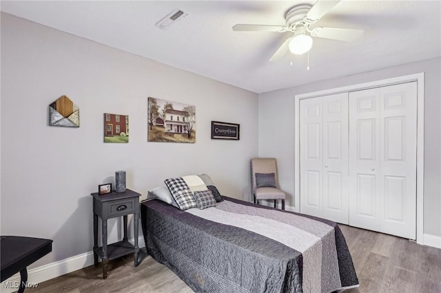 bedroom with visible vents, baseboards, a closet, and wood finished floors