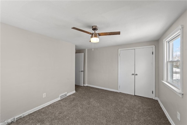 unfurnished bedroom featuring ceiling fan, a closet, visible vents, carpet flooring, and baseboards