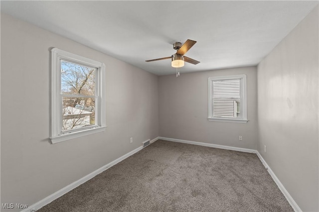 empty room featuring carpet flooring, baseboards, a ceiling fan, and visible vents