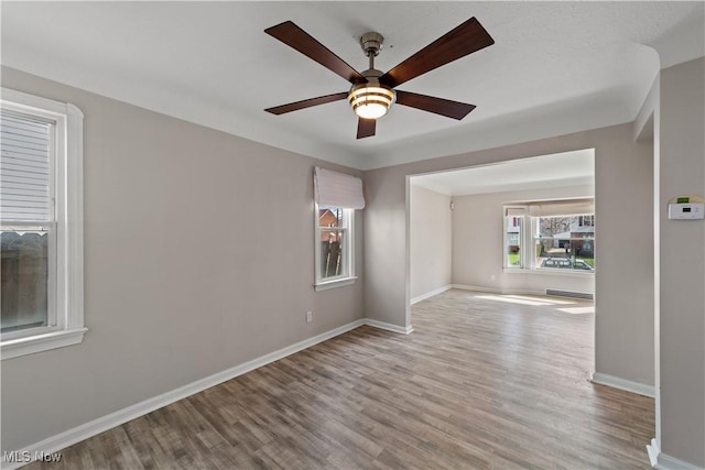 unfurnished room with baseboards, a ceiling fan, and wood finished floors