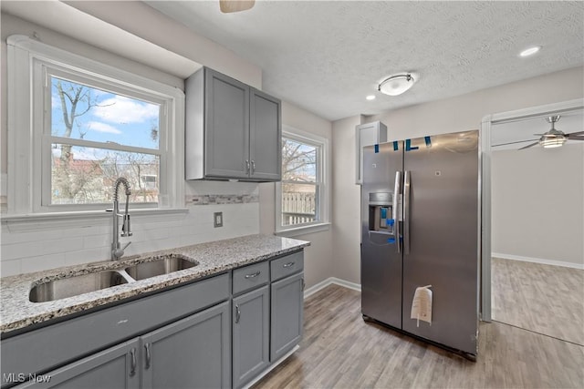 kitchen with stainless steel fridge with ice dispenser, gray cabinetry, a sink, and a ceiling fan