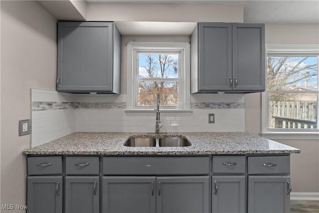 17207 Stockbridge Ave, Cleveland, OH 44128 - kitchen with gray cabinetry, a sink, and tasteful backsplash