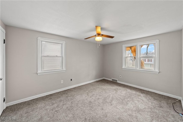 carpeted empty room with visible vents, baseboards, and a ceiling fan