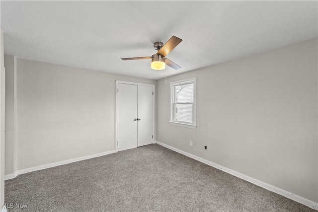 empty room featuring baseboards, a ceiling fan, and carpet