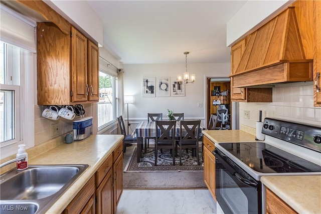 kitchen with electric range, custom range hood, a sink, brown cabinets, and light countertops