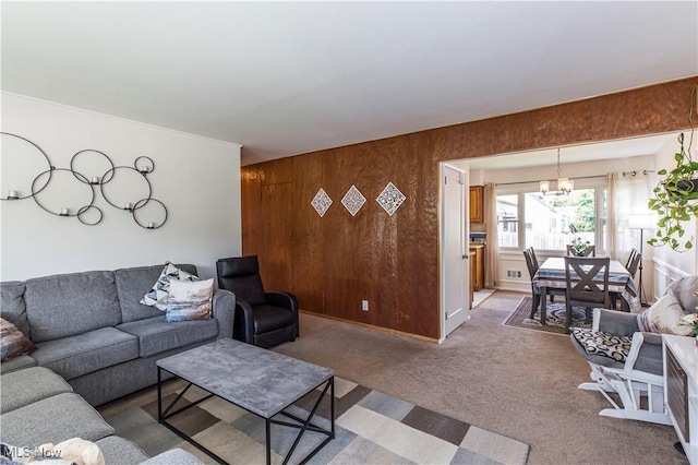 carpeted living area featuring a chandelier and wood walls
