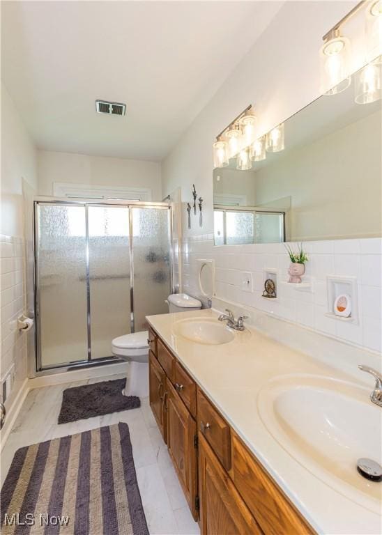 bathroom featuring tile walls, toilet, healthy amount of natural light, a shower stall, and double vanity