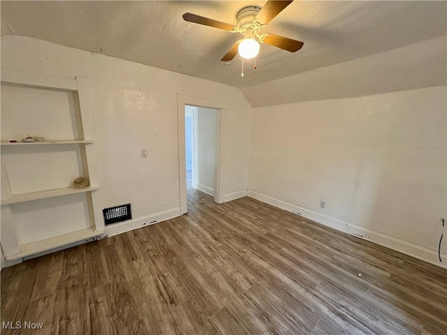 empty room featuring wood finished floors, ceiling fan, baseboards, and lofted ceiling