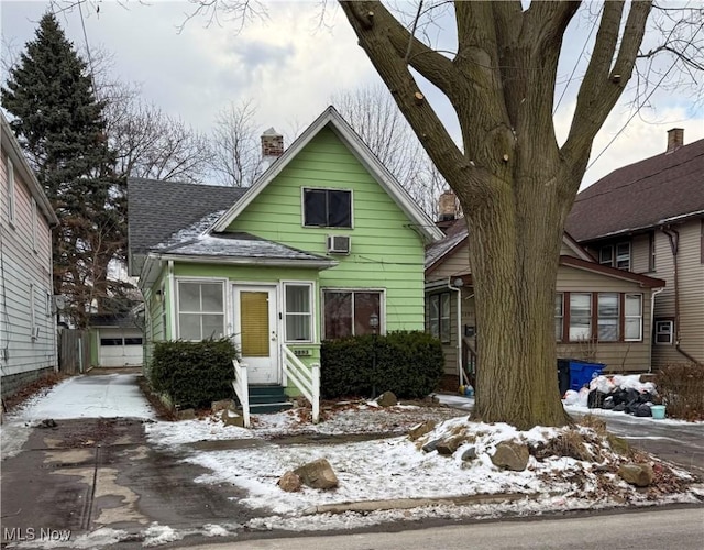 view of front facade featuring concrete driveway, roof with shingles, a chimney, entry steps, and a garage