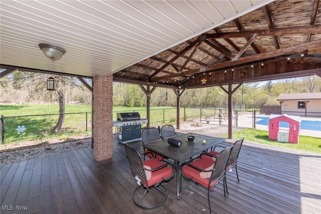 wooden terrace with a lawn, a grill, fence, and outdoor dining space
