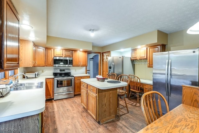 kitchen featuring stainless steel appliances, light wood-style floors, light countertops, and a sink