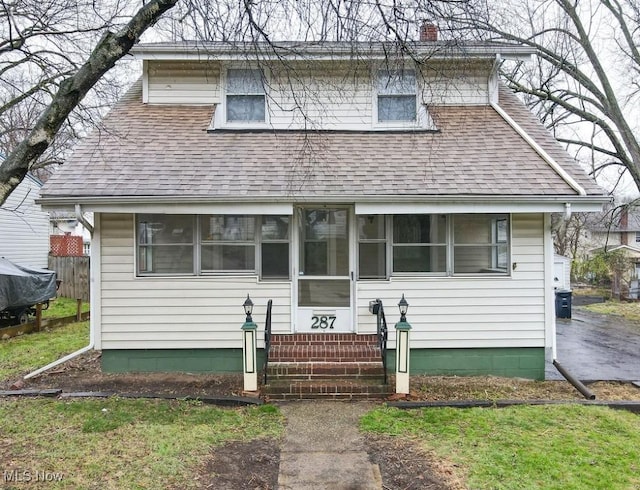 view of front of property with entry steps, a chimney, and a shingled roof
