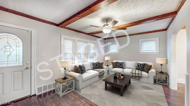 living room with wood finished floors, beamed ceiling, and visible vents