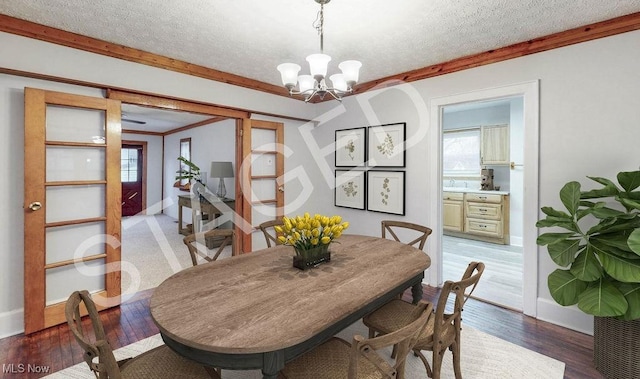 dining space with a textured ceiling, crown molding, a notable chandelier, and plenty of natural light