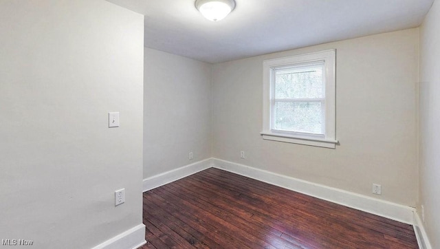 empty room with dark wood-type flooring and baseboards
