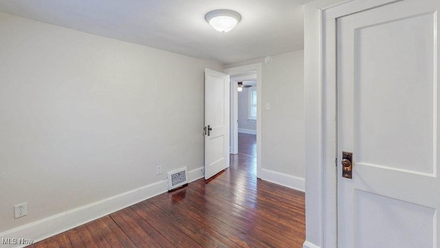 empty room with wood-type flooring, visible vents, and baseboards