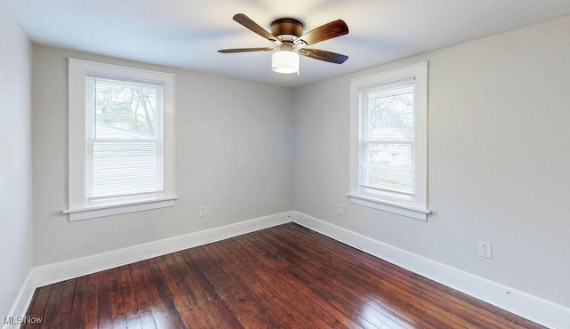 empty room with a wealth of natural light, dark wood-style flooring, and baseboards