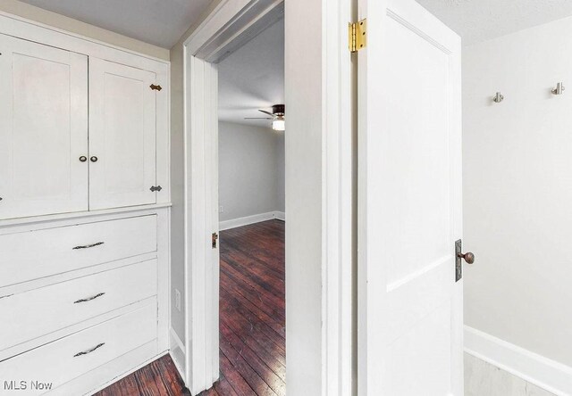 corridor with dark wood-style floors and baseboards